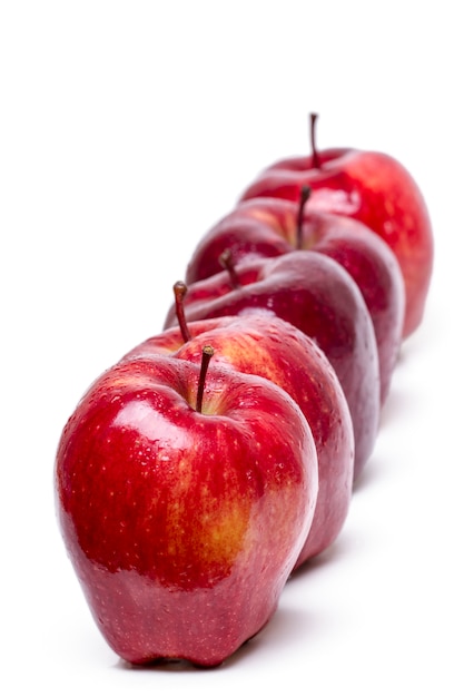 Zamyka w górę widoku niektóre czerwoni jabłka odizolowywający na białym tle z rzędu.
