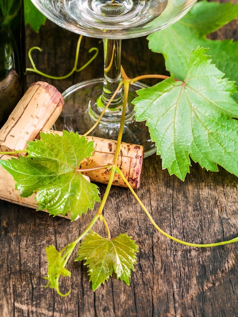 Zamyka w górę wino korka z gronowym winogradem i wina szkłem na nieociosanym drewnianym stole.