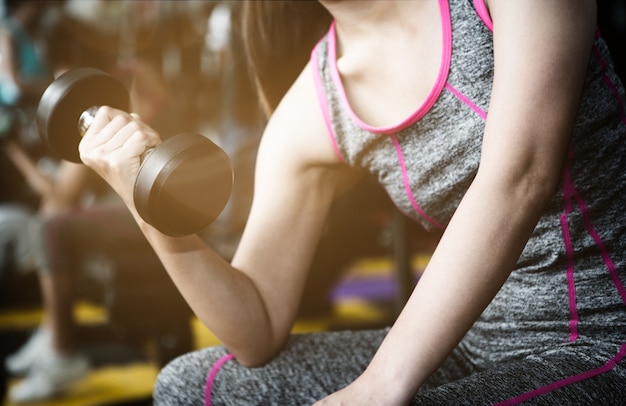 Zamyka w górę wizerunku trzyma dumbbell w gym sprawności fizycznej kobieta