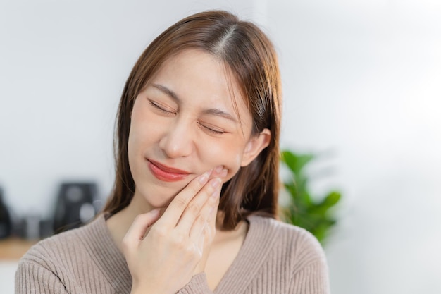Zamykanie oczu azjatycka młoda kobieta dotykająca policzka wyraz twarzy od bólu zęba próchnica lub nadwrażliwość zębów mający problem z zębami lub zębami lub stan zapalny cierpiący na zdrowie wrażliwi zęby ludzie