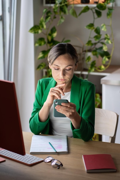 Zamyślona bizneswoman przewija media społecznościowe, czyta na telefonie potrzebne artykuły i wiadomości w Internecie