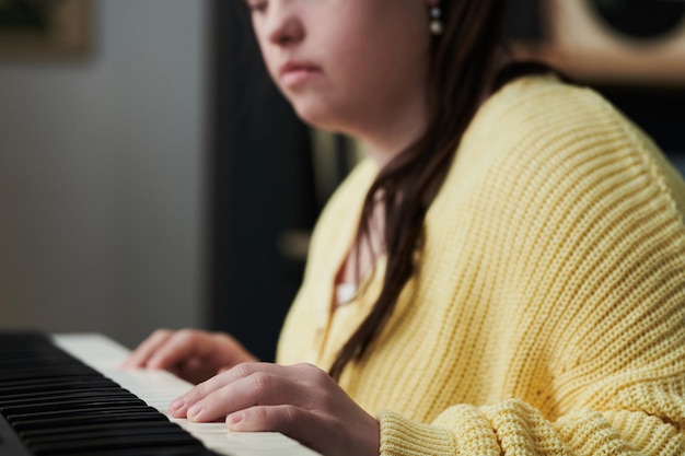 Zamyślona kobieta z niepełnosprawnością grająca na pianinie