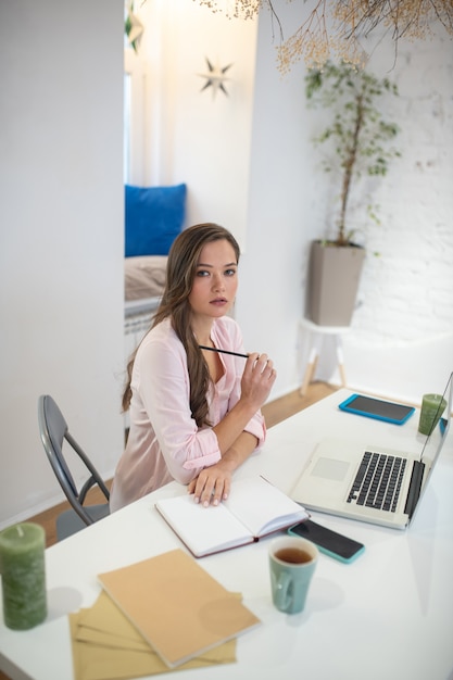 Zamyślona młoda kobieta siedzi w swoim biurze, myśląc o swojej pracy