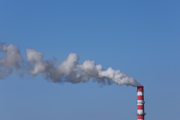 Zanieczyszczanie powietrza dymem z komina przemysłowego na zewnątrz przed emisjami CO2 błękitnego nieba