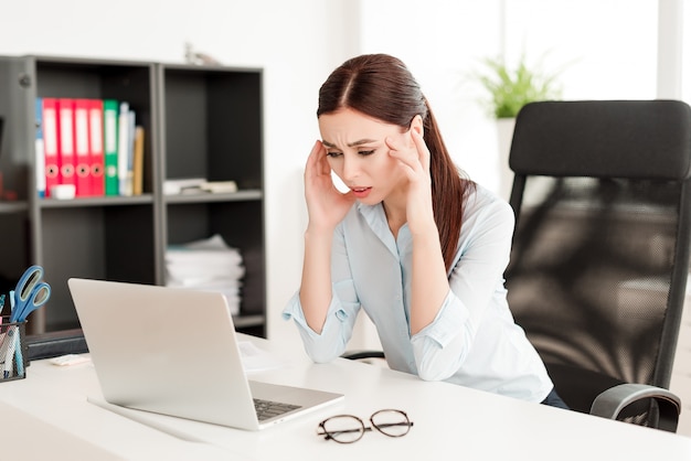 Zaniepokojona kobieta próbuje rozwiązać problem biznesowy przy laptopem