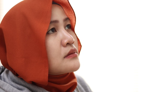 Zdjęcie zaniepokojona, smutna azjatycka muzułmańska kobieta patrzy w górę, myśląc o czymś z pustym spojrzeniem.