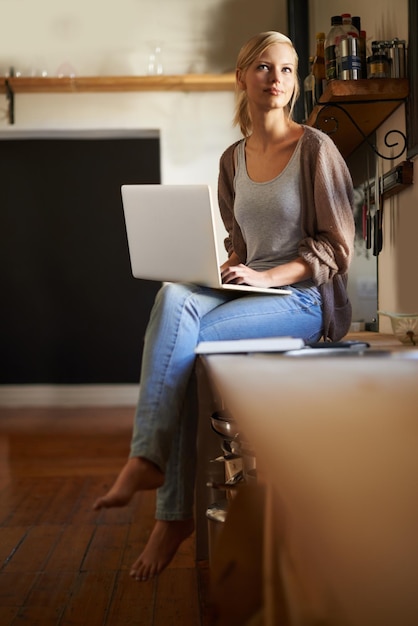 Zanotowanie kilku pomysłów na przepisy Ujęcie atrakcyjnej młodej kobiety korzystającej z laptopa podczas relaksu w domu