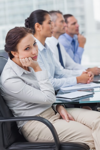 Zanudzony bizneswoman patrzeje kamerę podczas gdy uczęszczający prezentację