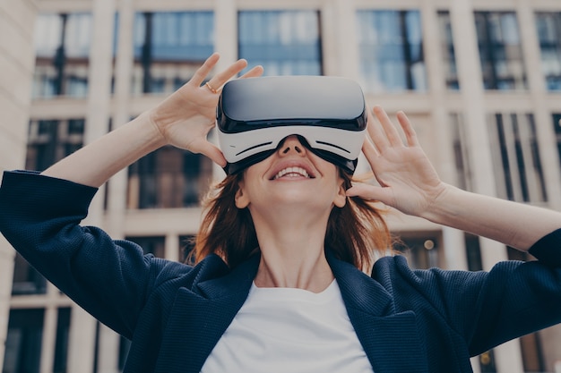 Zanurzona kobieta patrząca w wirtualną rzeczywistość podczas noszenia przenośnego vr stojącego na ulicy miasta