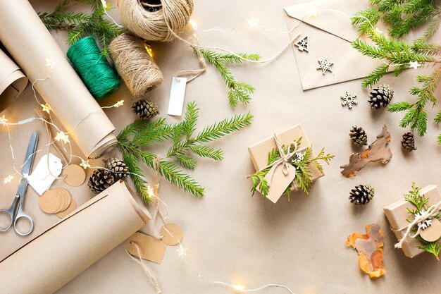 Zapakuj prezent na Boże Narodzenie i Nowy Rok w ekologiczne materiały: papier pakowy, żywe gałęzie jodły, szyszki, sznurek. Tagi z makietą, naturalny wystrój, hand made, DIY. Świąteczny nastrój. Boże Narodzenie w tle