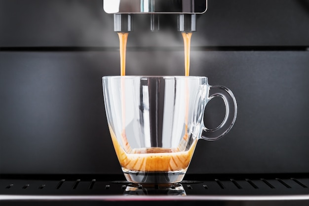 Zdjęcie zaparzoną kawę wlewa się z ekspresu do szklanej filiżanki