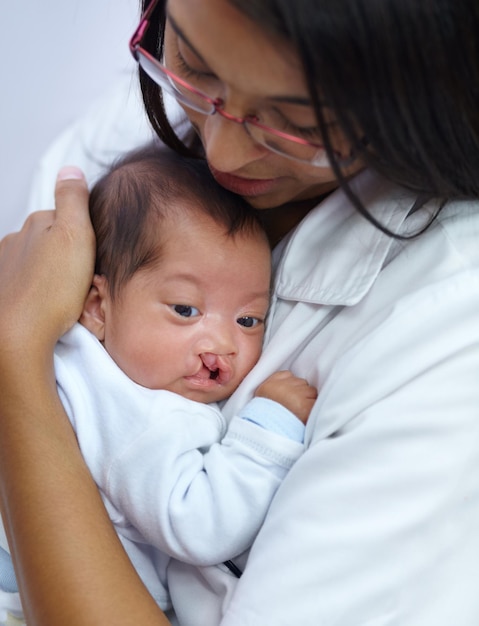 Zapewnienie komfortu jest kluczowe w jej zawodzie Ujęcie młodej pielęgniarki trzymającej dziecko z rozszczepem podniebienia