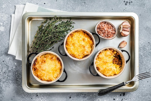 Zapiekanka Owczarka Irlandzkiego z mięsem mielonym, puree ziemniaczanym i skórką z sera cheddar. Szare tło. Widok z góry.