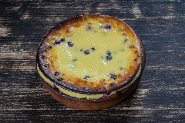 Zapiekanka z sera na słodko z czarną porzeczką i kaszą manną na drewnianym stole Miska ceramiczna z zapiekanym serem