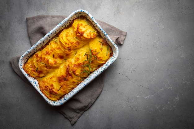 Zapiekanka ziemniaczana - graten (pieczone ziemniaki ze śmietaną i serem) z rozmarynem i widelcami (turecka nazwa; kremali patates)