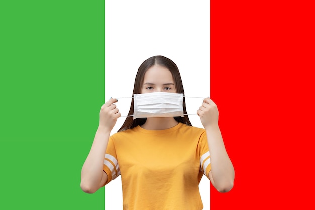 Zapobieganie koronawirusowi we Włoszech Młoda dziewczyna zakłada antybakteryjną maskę medyczną na tle flagi
