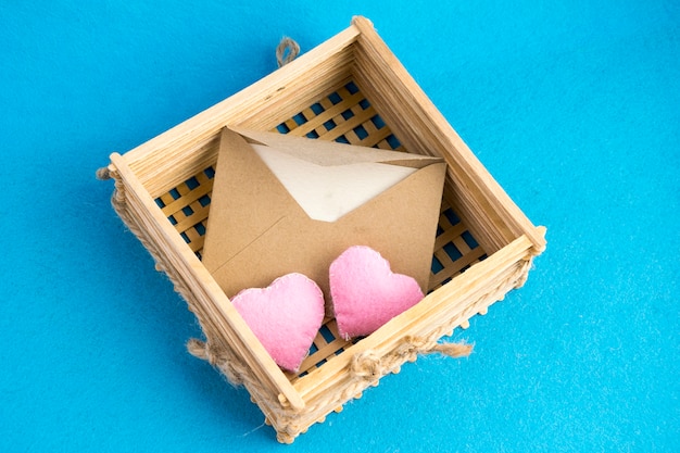 Zaproszenie lub list miłosny w starej drewnianej wiklinie z pluszowymi sercami na niebiesko