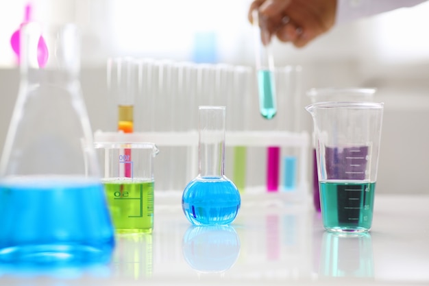 Żarówka przemysłu chemicznego z niebiesko-purpurowymi płynnymi probówkami laboratoryjnymi stoi na stole w laboratorium badania płynów testowanie substancji rozwojowych trucizny dodatki stabilizatory aromaty sprzątanie domu
