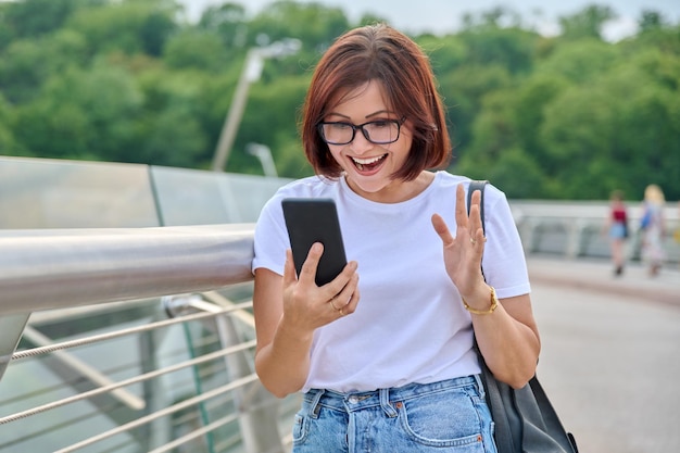 Zaskoczona kobieta w średnim wieku patrząca na ekran smartfona