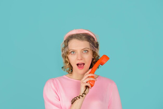 Zaskoczona kobieta z retro telefonem dziewczyna trzyma słuchawkę telefon stacjonarny kobieta w różowej sukience