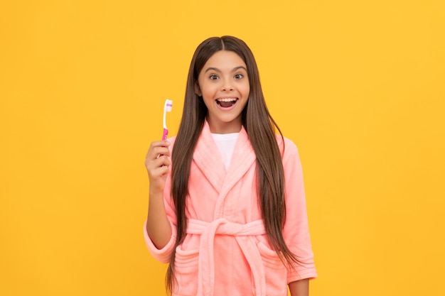 Zaskoczona nastolatka w domu frotte szlafrok trzyma szczoteczkę do zębów