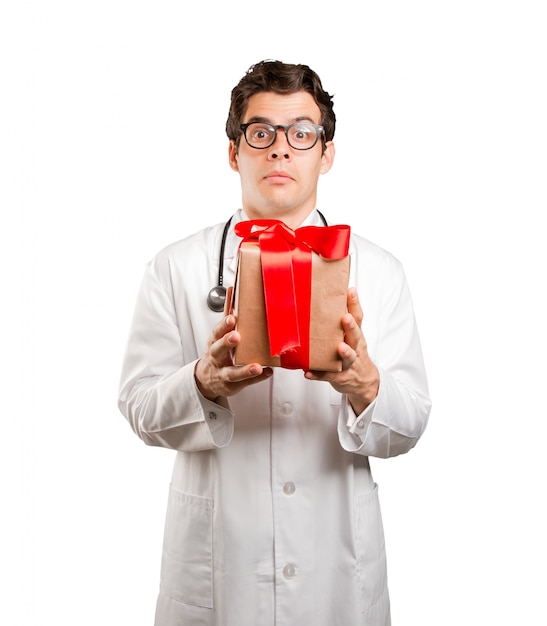 Zaskoczony lekarz posiadający prezent na białym tle