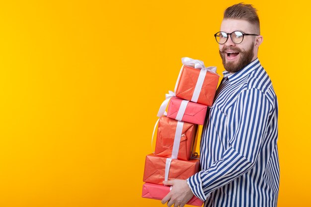Zaskoczony, młody hipster facet w okularach, trzymając duży stos pudełek na prezent