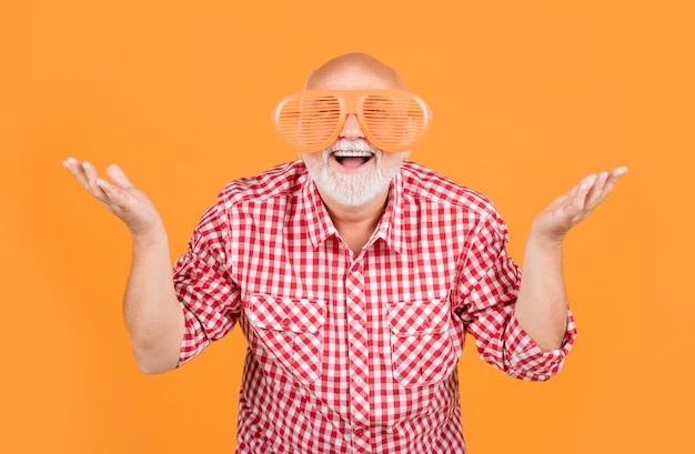 Zdjęcie zaskoczony starszy mężczyzna lub dziadek w okularach na żółtym tle