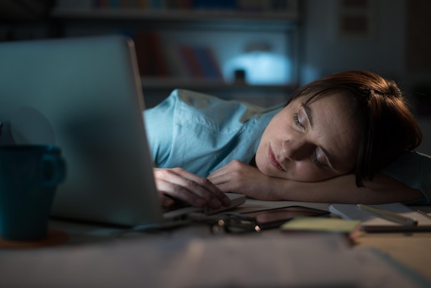 Zaspana kobieta pracująca z laptopem