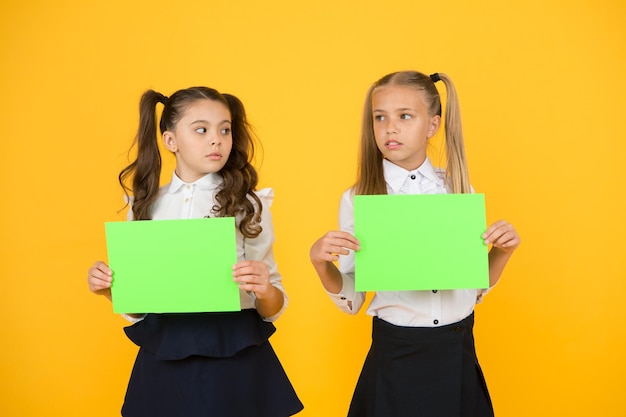 Zastanawianie się nad pracą domową Małe dzieci trzymające puste kartki do pracy egzaminacyjnej na żółtym tle Małe dziewczynki z czystymi zielonymi papierami do prac projektowych lub badawczych Miejsce na kopię do pracy papierkowej