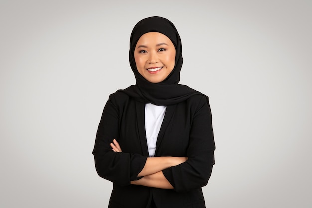 Zaufała muzułmańska bizneswoman w czarnym hidżabie i blazerze stoi z skrzyżowanymi ramionami