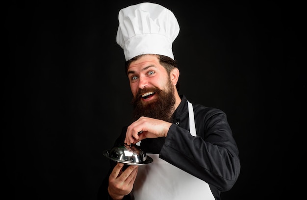 Zawód kucharza i koncepcja ludzi mężczyzna kucharz kucharz trzyma klosz do serwowania i prezentacji kucharza