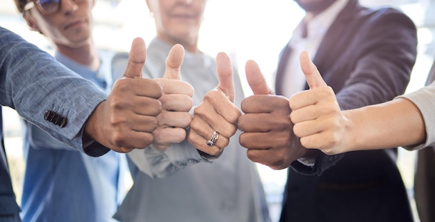 Zawsze jest sukces pod koniec ciężkiej pracy Zbliżenie grupy nierozpoznawalnych biznesmenów pokazujących razem kciuki w biurze