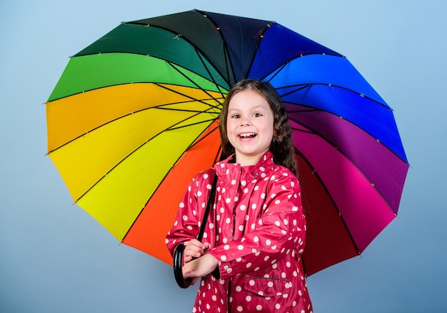 Zawsze po deszczu jest tęcza Ciesz się koncepcją deszczu Sezon jesienny Dziewczynka z radością trzymaj kolorowy tęczowy parasol Deszczowa pogoda z odpowiednim ubraniem Zabawa w deszczowy dzień Szczęśliwy spacer pod parasolem