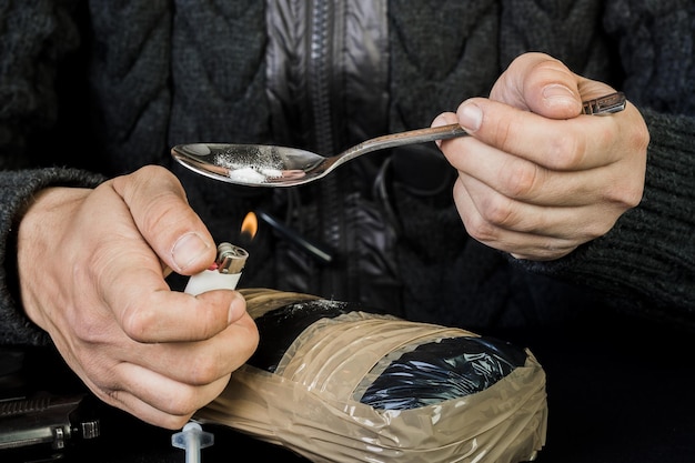 Zażywanie narkotyków narkotyki Mężczyzna przygotowujący heroinę za pomocą łyżki i zapalniczki