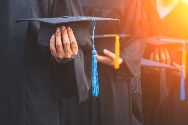 Zbliżenie absolwentów trzymających kapelusze w ręku