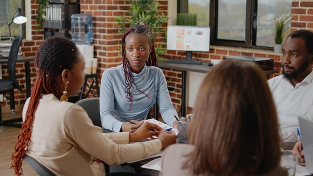 Zbliżenie African American Kobieta Mówi O Projekcie Biznesowym Z Kolegami W Sali Konferencyjnej. Dorosły Omawiający Pomysły Na Strategię I Prezentację Marketingową Z Kolegami W Pracy.