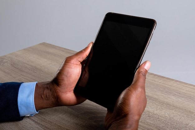 Zbliżenie: Afroamerykanin biznesmen trzymający cyfrowy tablet na szarym tle