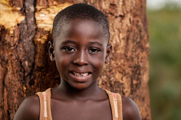 Zdjęcie zbliżenie afrykańskie dziecko pozowanie w pobliżu drzewa