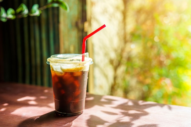 Zbliżenie Americano Ice Coffee lub czarna kawa w filiżance kubek na szklane biurko drewniane biurko w kawiarni w kawiarni w gardenpodczas koncepcji pracy biznesowej