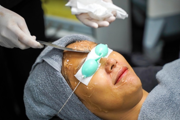 Zbliżenie azjatycka piękna kobieta otrzymująca żel do skóry w celu przygotowania kolorowej terapii światłem