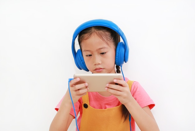 Zbliżenie Azjatyckie Dziecko Dziewczynka Nosi Słuchawki I Ciekawą Grę Na Smartfonie Na Białym Tle