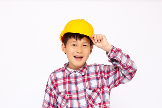Zbliżenie azjatyckiego chłopca w kasku, uśmiechającego się i patrzącego w kamerę, stojącego na białym tle na białej powierzchni