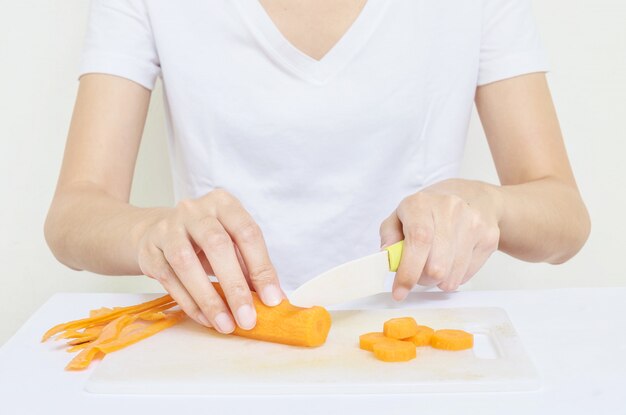 Zbliżenie azjatykcia kobieta przygotowywa dla gotować z świeżą marchewką plastikowym nożem w jej ręce