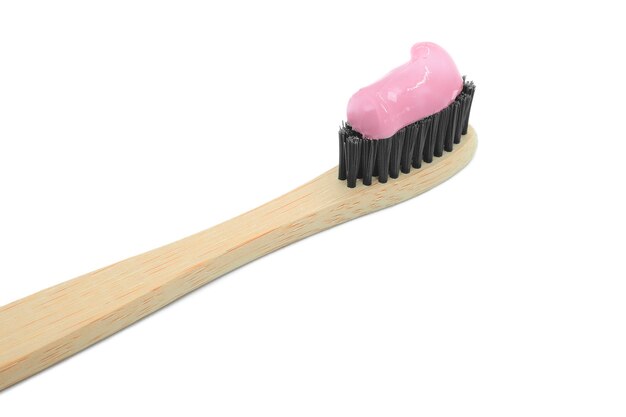 Zbliżenie bambusowej szczoteczki do zębów z różową pastą do zębów na białym tle Higiena osobista jamy ustnej