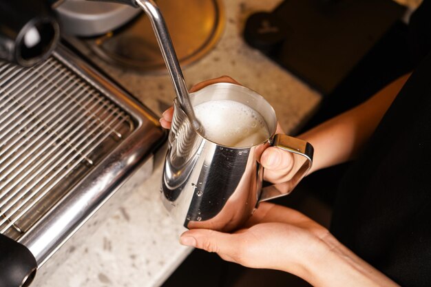 Zbliżenie barista przygotowującego piwo do kawy latte