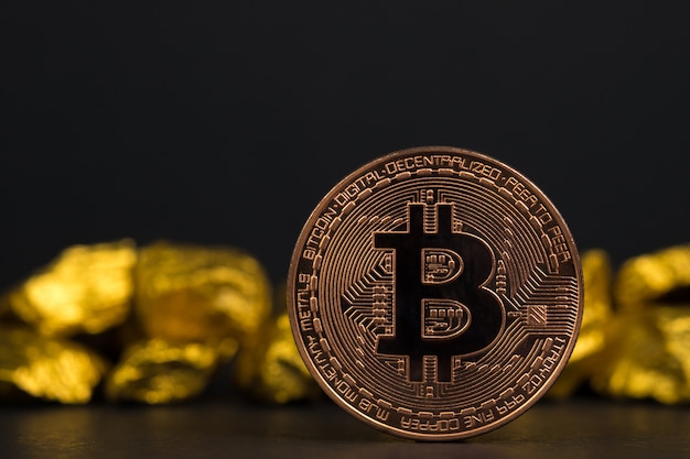 Zbliżenie bitcoin waluty cyfrowej i samorodek złota na czarnym tle,