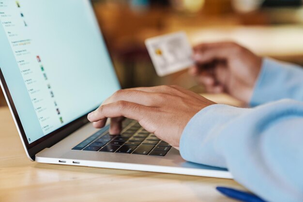 Zbliżenie Biznesmena Pracującego Na Laptopie W Pomieszczeniu, Trzymającego Kartę Kredytową