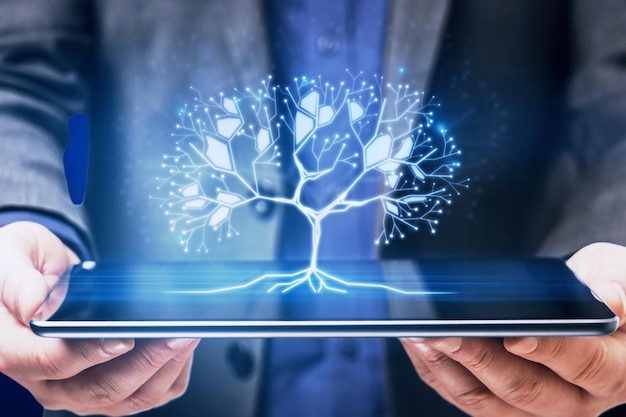 Zbliżenie biznesmena ręki trzymającej tablet ze świecącym cyfrowym wielokątnym drzewem na niebieskim tle Technologia sieciowa i koncepcja bazy danych