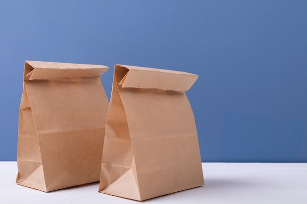 Zdjęcie zbliżenie: brązowe papierowe torby na lunch na stole na niebieskim tle z miejsca na kopię